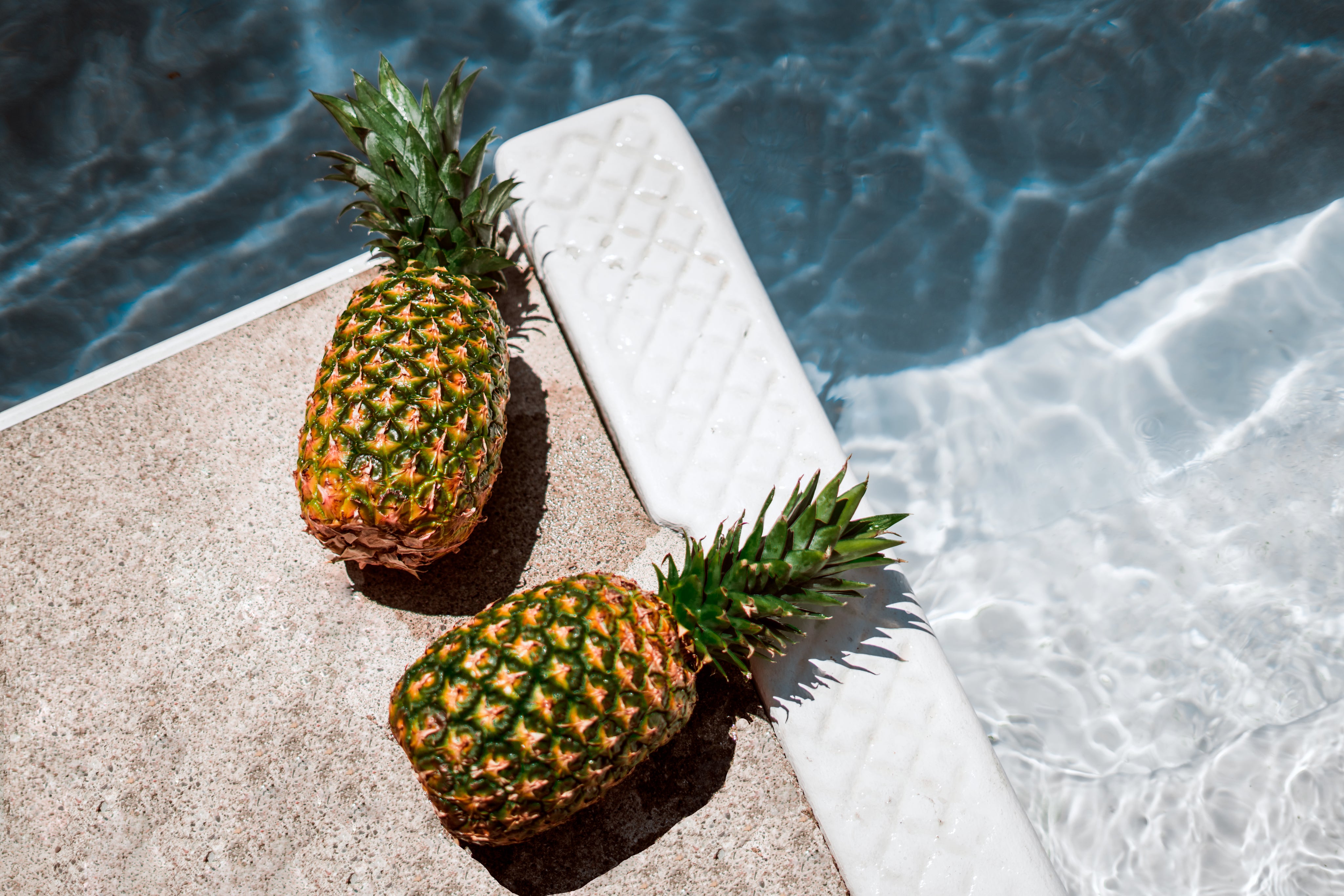 deux ananas au bord d'une piscine 
